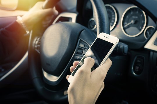 Driver With Mobile Phone In The Car Driving