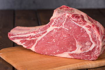 Raw Grass Fed Prime Rib Meat with a Chef Knife on a Wood Board