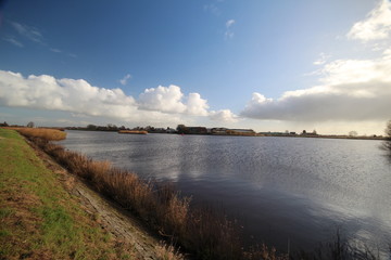 Wide angle overview of blue sky, white clouds and river Hollandse IJssel in Moordrecht, Netherlands