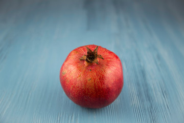 Ripe red pomegranate in the middle of the blue wooden background
