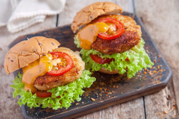 chicken burgers with vegetables on a wooden table