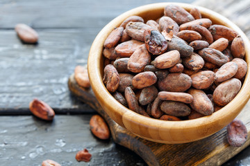 Fragrant cocoa beans in wooden bowl closeup.