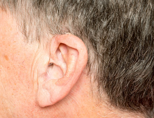 Close up of a tiny modern hearing aid behind ear