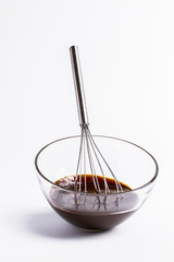 whisk, bowl with chocolate on a white
