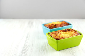 Baked cottage cheese casserole in bright turquoise and green baking dishes and a cup of cocoa