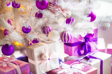 Closeup of a large stack of wrapped Christmas presents of varying sizes and shapes in Xmas interior.