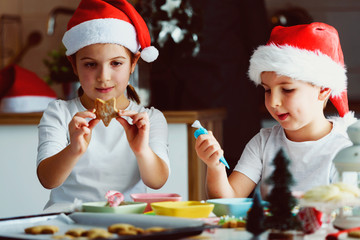 Two happy children decorating cookies for holidays at home