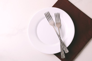 Fototapeta na wymiar Food background. White empty plate, cutlery, napkin. Top view, copyspace.