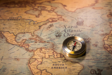 Fototapeta na wymiar Old vintage retro golden compass on ancient map. Selective focus, shallow depth of field. Concept of world travel, sightseeing and tourism.