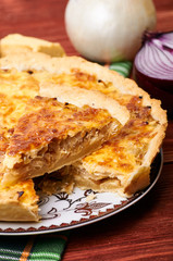 Appetizing French onion pie in a cut. Portion of vegetable vegetarian pie with cheese crust. The table is served for dinner. Simple rustic homemade food.