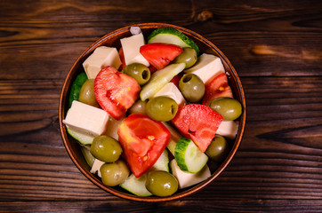 Greek salad in a bowl on wooden table. Top view