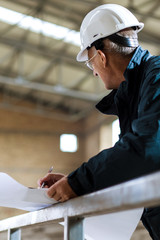 Senior construction manager controlling building site with plan.