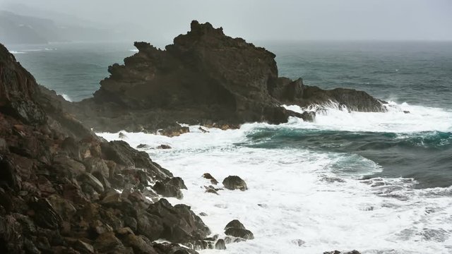 Storm and rain with tall waves hitting the rocks at Playa de Nogales beach in La Palma, Spain. 