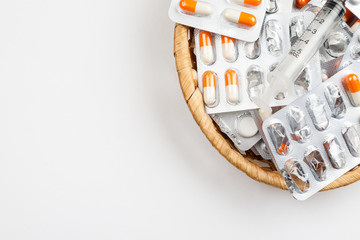 medicines in blister packs in a wicker basket on a white background