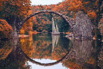 Rakotzbrücke (Rakotzbrucke, Teufelsbrücke) in Kromlau, Sachsen, Deutschland. Bunter Herbst, Spiegelung der Brücke im Wasser bilden einen vollen Kreis