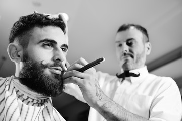 Client during beard shaving in barber shop