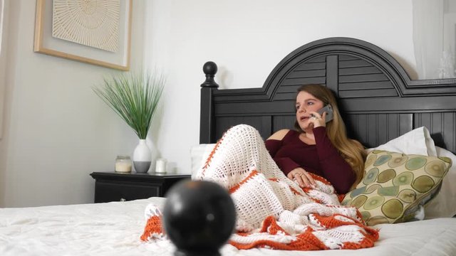 Attractive gossiping woman talking on smartphone in her bedroom