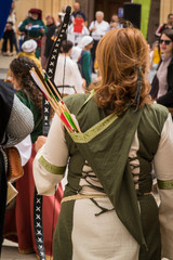 Young female archer dressed in traditional ancient medieval clothing with quiver of arrows and bow,...