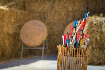Quiver of traditional feathered arrows in front of traditional ancient medieval straw practice...