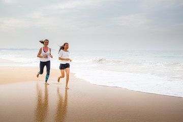 Fototapeta na wymiar two women is jogging the seashore on an overcast day