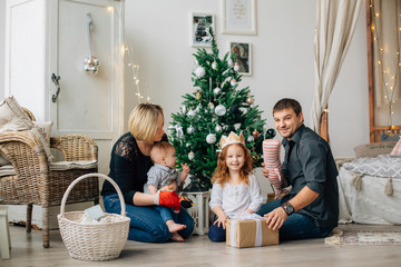 Young happy family of four having fun near christmas tree. Happy new year concept. Cheerful parents and kids
