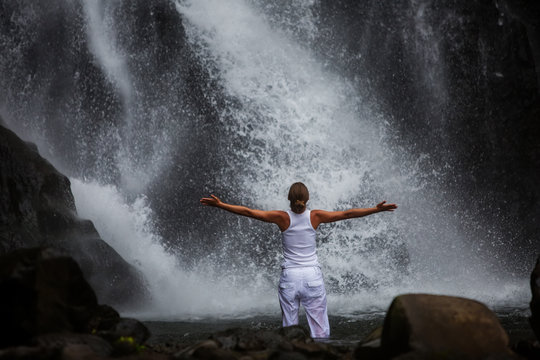 Woman practices yoga at Gitgit waterfall on Bali in indonesia