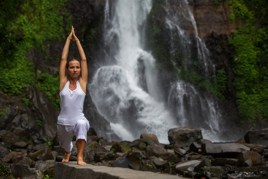 Woman practices yoga at Gitgit waterfall on Bali in indonesia