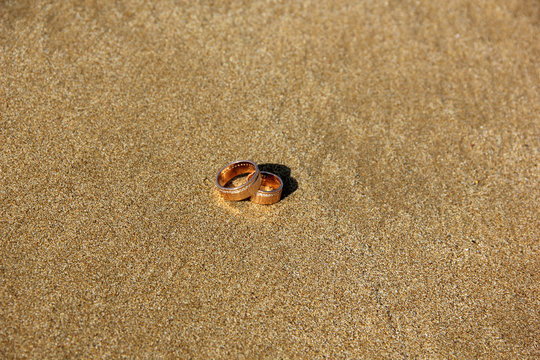 Wedding rings lay on the sand beach