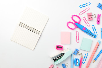 Stationary concept, Flat Lay top view Photo of Scissors, pencils, paper clips, sticky note,staple with blank note pad in pink and blue tone on white background with copy space