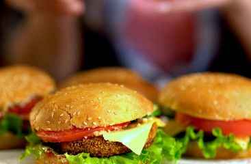 Hamburger fast food with ham on wooden board. Group of hamburger. Human hand holding cheeseburger. Semi-finished products.