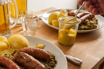 Mann nimmt Senf zu deftigen Grünkohl, Pinkel und Mettwurst