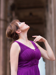 Beautiful woman in purple dress near the column. People