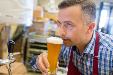 brewer in uniform tasting beer at the brewery