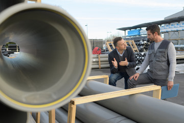 Workers stood talking by large tube