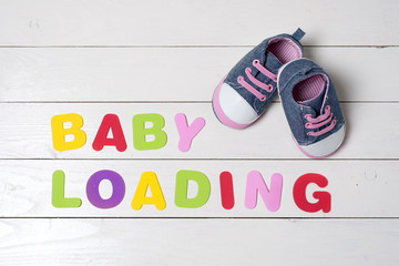 Baby shoes on white wooden table.