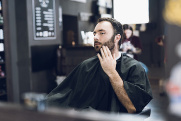 A man sits in a barber's chair in a man's barbershop, where he came to cut his hair.