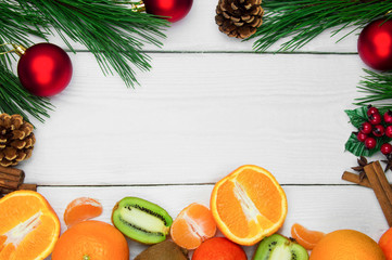 Fruit orange, tangerine and kiwifruit. Branch christmas tree and red ball with cone and cinnamon sticks on white wooden vintage background