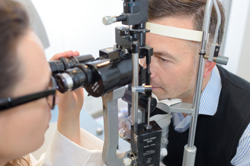 female optician in surgery giving man eye test