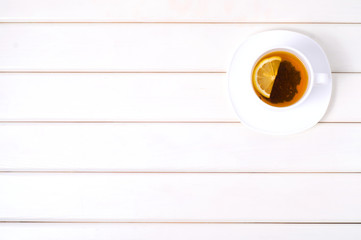 A cup of tea with lemon on a saucer