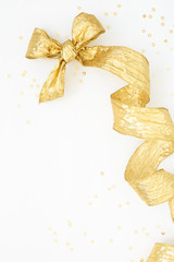 Golden Bow & decorative helix ribbon with gold tinsel on white. Vertical Festive background. Holiday preparations, Boxing Day. Overhead view
