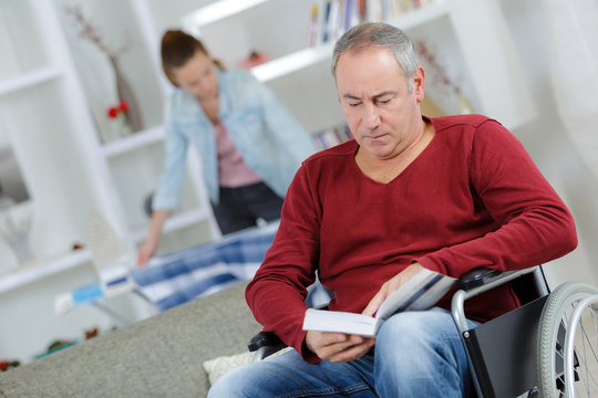 man on wheelchair reading a book