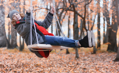 Girl in autumn city park in leaf fall. Young beautiful mother wi