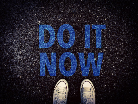 Do it now word and sneakers shoes on grunge road