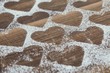 Heart shape made of icing or powdered sugar on a dark wooden background