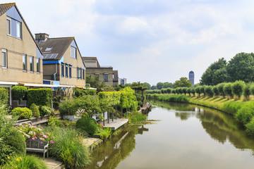 Fototapeta na wymiar Residential houses on the waterside with a water tower on the background located in Rokkeveen, Zoetermeer.