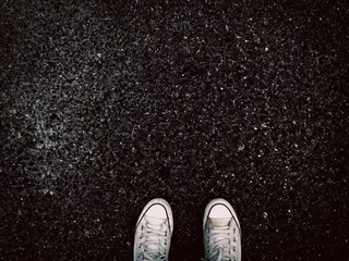 White sneaker shoe on dark grunge road background texture with copy space