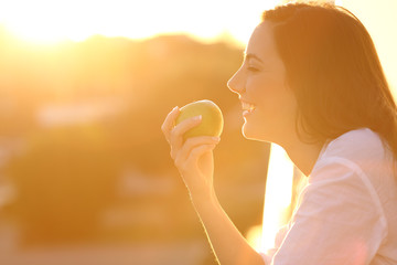 Profile of a woman eating an apple at sunset