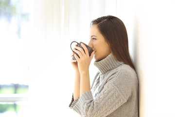 Woman drinking coffee looking through a window