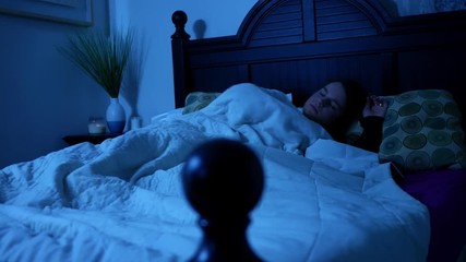 Woman tossing and turning in her bed under the moonlight ALT