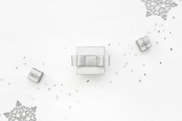 Three silver gift boxes, snowflakes and confetti on white background. Winter Holiday card. Boxing Day concept. Diagonal decoration. Top view.